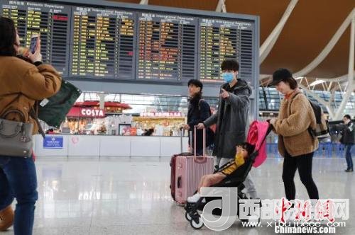 旅客帶著孩子前往辦票柜臺(tái)辦理登機(jī)手續(xù)?！∫罅⑶?攝