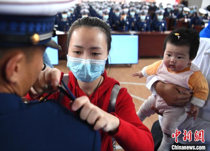 新消防員楊振的妻子彭莉與女兒現(xiàn)場(chǎng)見(jiàn)證丈夫加入“火焰藍(lán)”的神圣時(shí)刻。　劉忠俊 攝