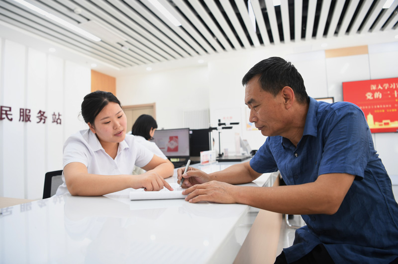 2023年5月23日，河北雄安新區(qū)容東片區(qū)南文營社區(qū)居民（右）在社區(qū)便民服務(wù)站辦理業(yè)務(wù)。